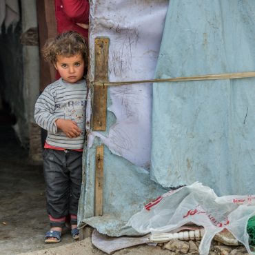 Kind in einem Flüchtlingslager in Syrien schaut verängstigt in die Kamera.